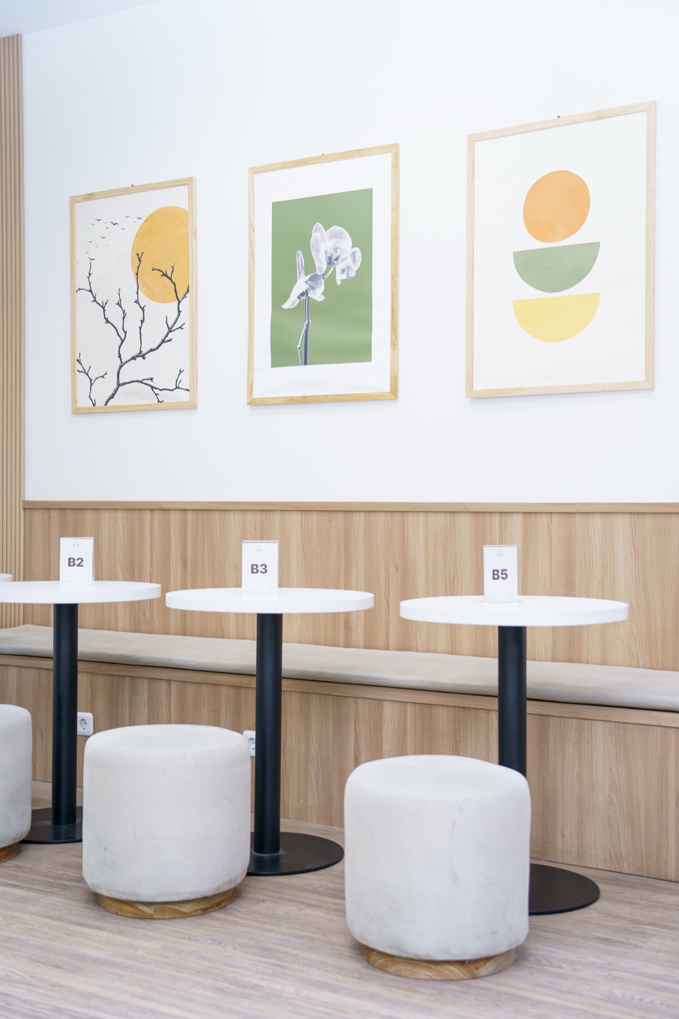 Framed prints above the panelled wall, with café tables and stools
